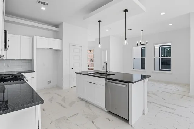 a kitchen with granite countertop a refrigerator and a stove top oven