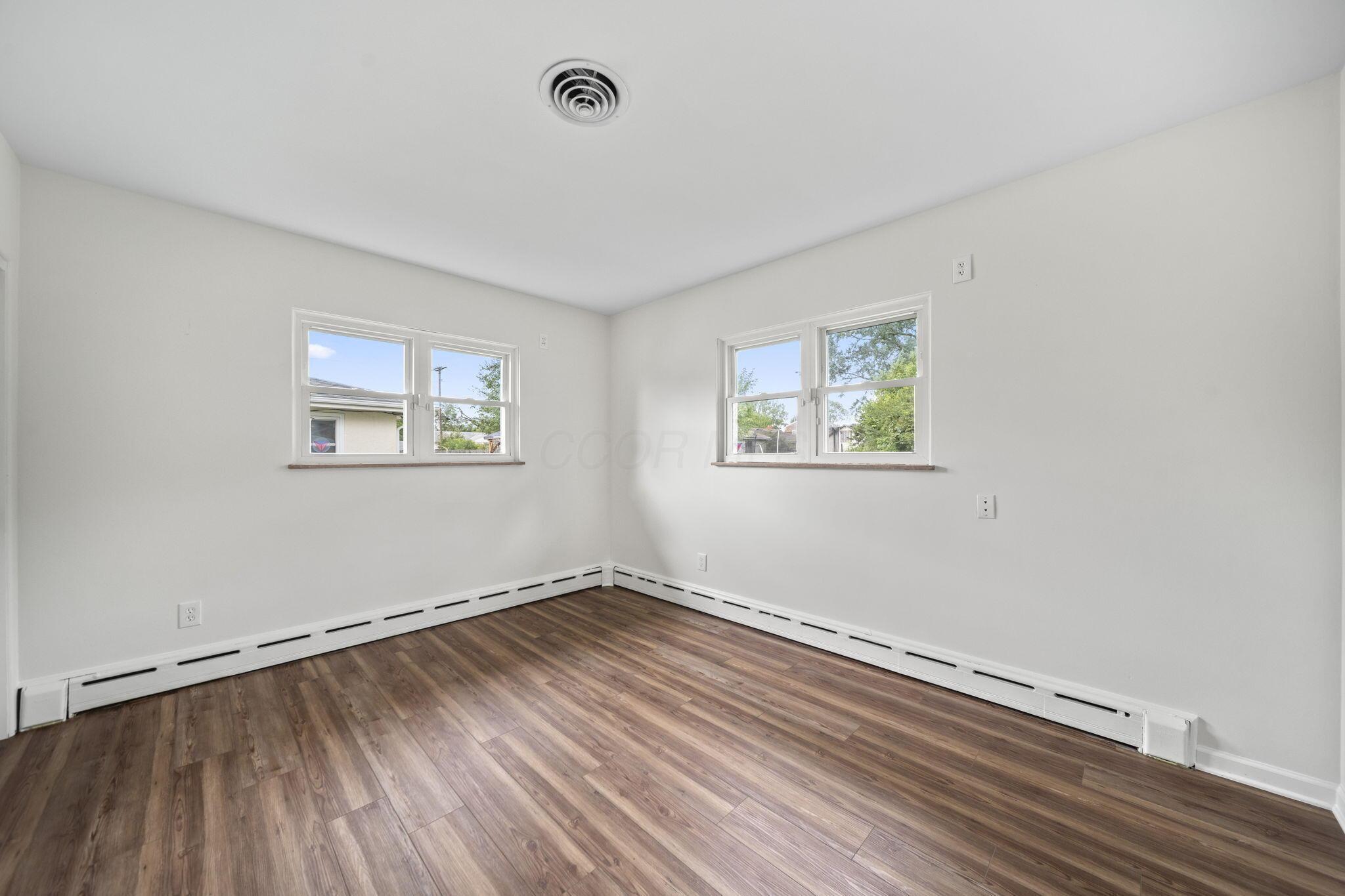 3496 Wicklow Road Columbus, OH 43204 - Photo 21 of 53 LVP flooring, white walls, two white-trimmed windows, and baseboard heating