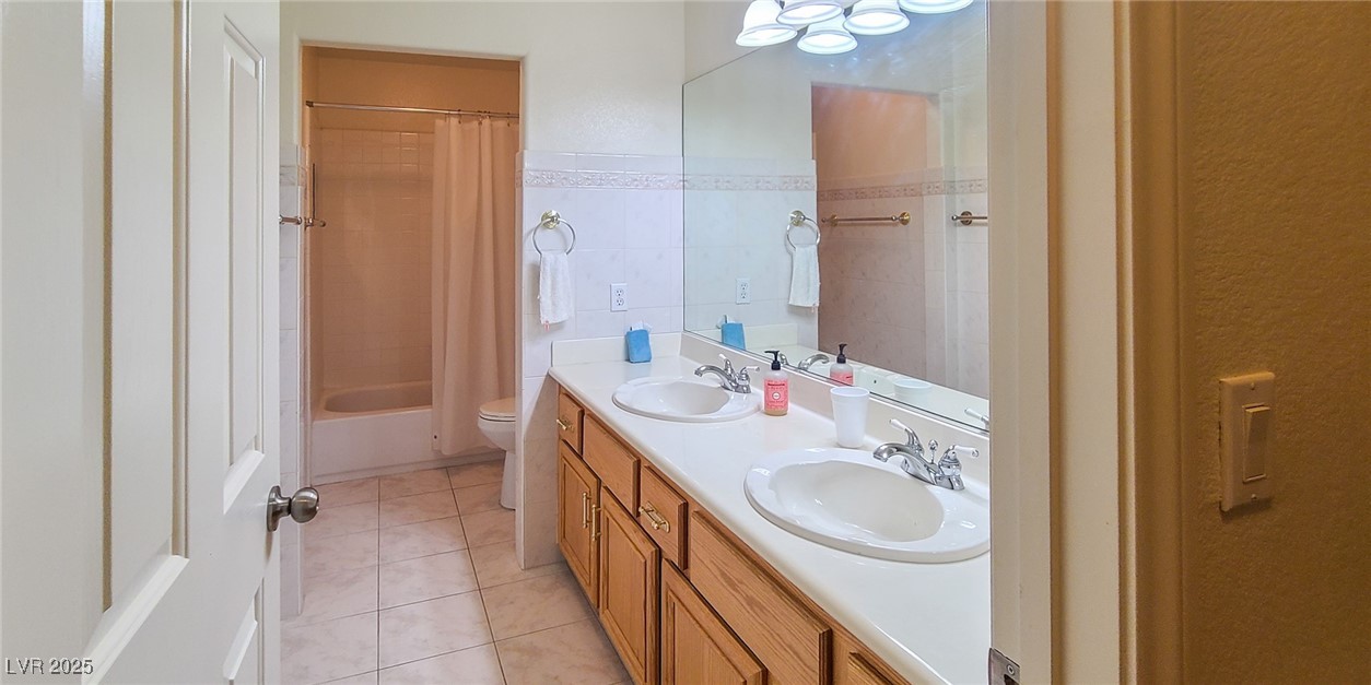4100 Highland Castle Court Las Vegas, NV 89129 - Photo 18 of 49 Bathroom featuring double vanity, light tile patterned flooring, tile walls, and shower / bath combo with shower curtain