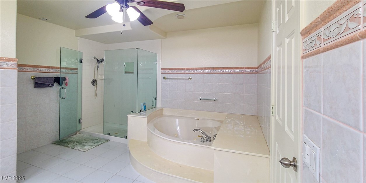 4100 Highland Castle Court Las Vegas, NV 89129 - Photo 23 of 49 Bathroom featuring tile walls, a whirlpool tub, a shower stall, a wainscoted wall, and tile patterned floors