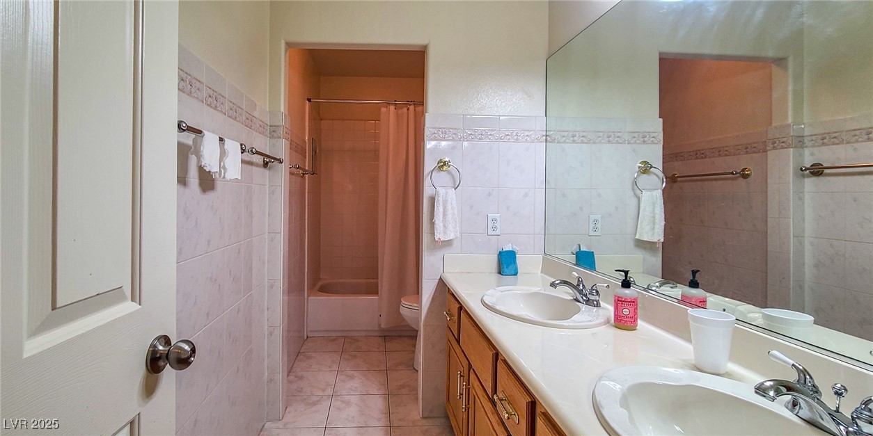 4100 Highland Castle Court Las Vegas, NV 89129 - Photo 29 of 49 Bathroom featuring tile walls, double vanity, light tile patterned flooring, and shower / bath combo