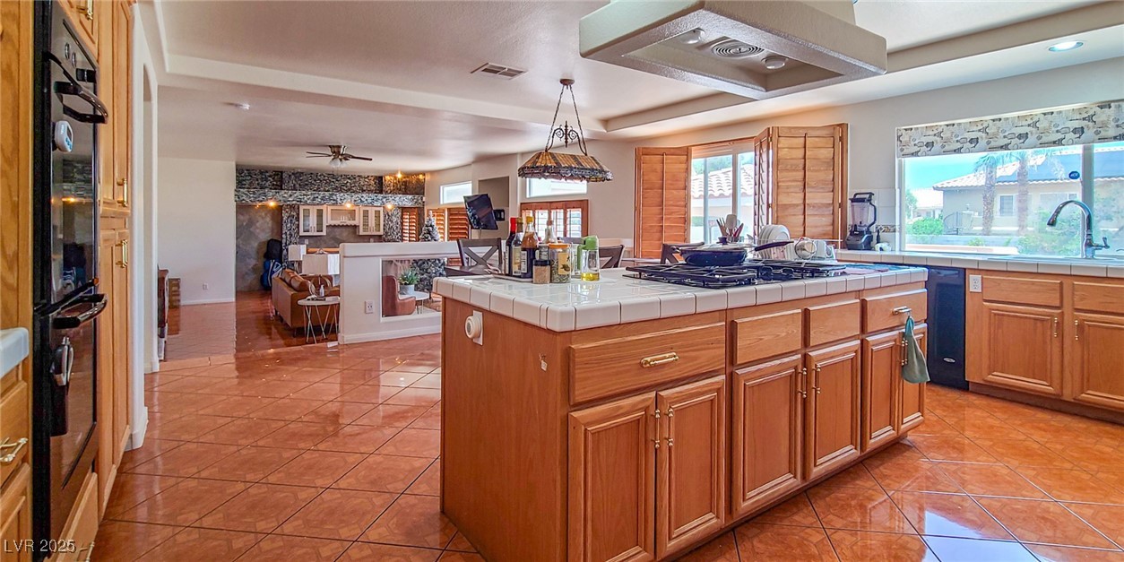 4100 Highland Castle Court Las Vegas, NV 89129 - Photo 49 of 49 Kitchen featuring tile counters, wall chimney exhaust hood, open floor plan, light tile patterned floors, and hanging light fixtures