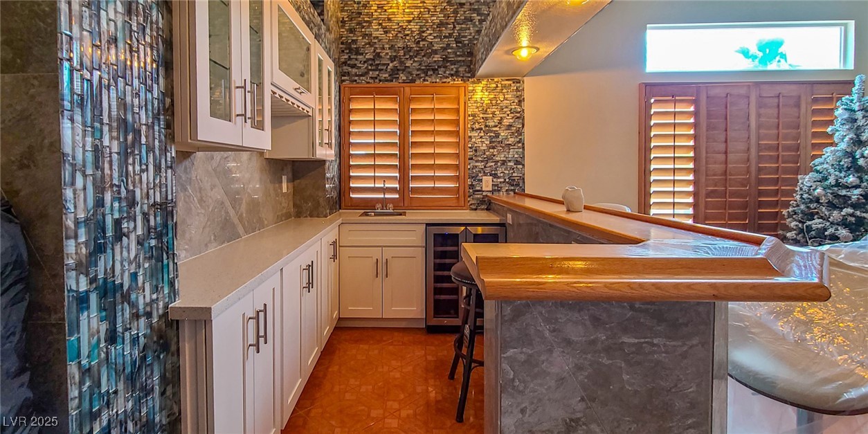4100 Highland Castle Court Las Vegas, NV 89129 - Photo 44 of 49 Indoor wet bar featuring wood counters, wine cooler, glass insert cabinets, tasteful backsplash, and white cabinetry