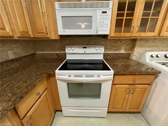 a kitchen with granite countertop white cabinets and white appliances