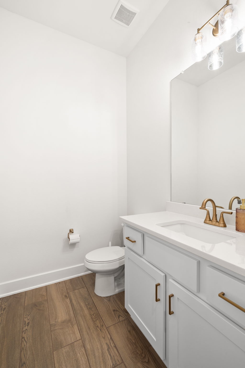 515 Watershield Cove Georgetown, TX 78633 - Photo 6 of 40 A refined bathroom features wood flooring and a classic vanity with a gleaming mirror.