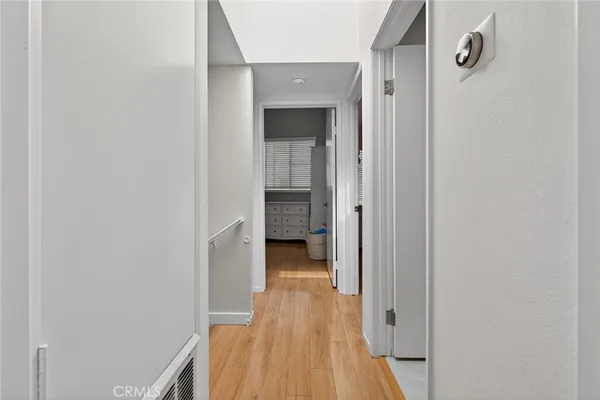 a view of a hallway with wooden floor and a bathroom