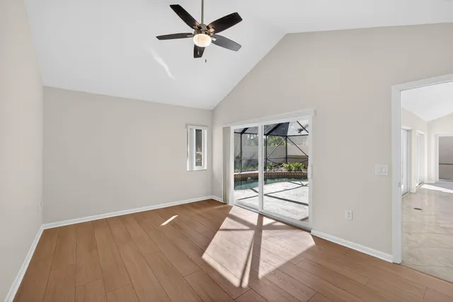 a view of an empty room with wooden floor and a ceiling fan
