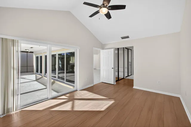 a view of an empty room with wooden floor and a window