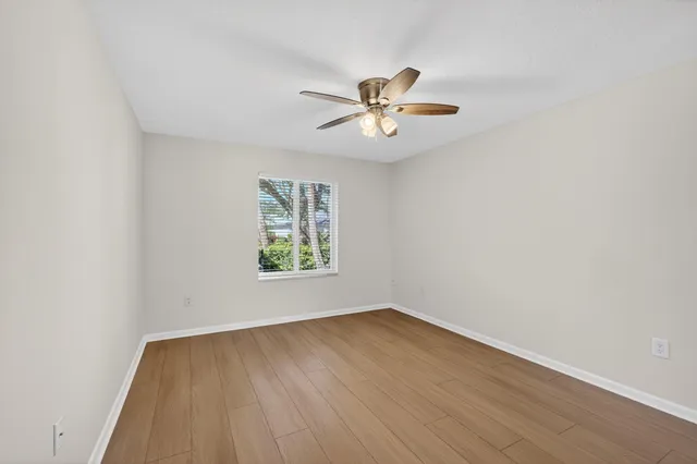 a view of empty room with wooden floor and fan