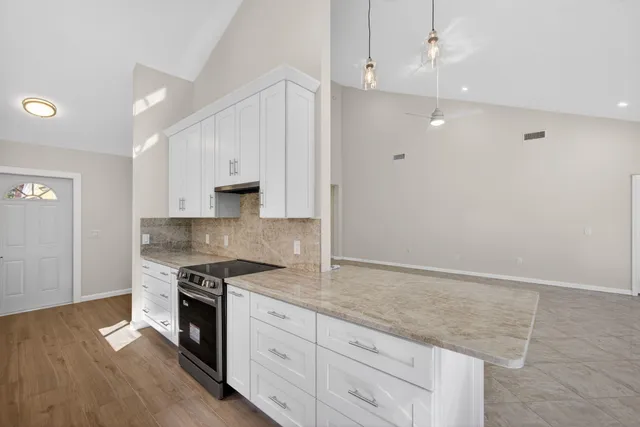 a kitchen with granite countertop cabinets stainless steel appliances and a wooden floor