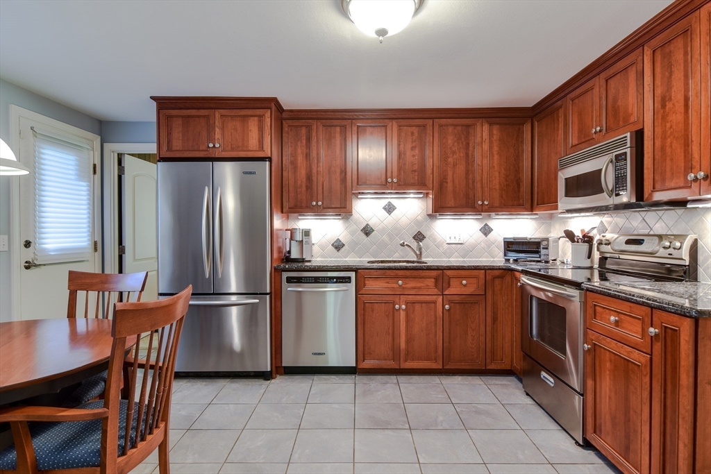 38 Stagecoach Drive Ashland, MA 01721 - Photo 9 of 29 a kitchen with stainless steel appliances granite countertop a refrigerator and wooden cabinets
