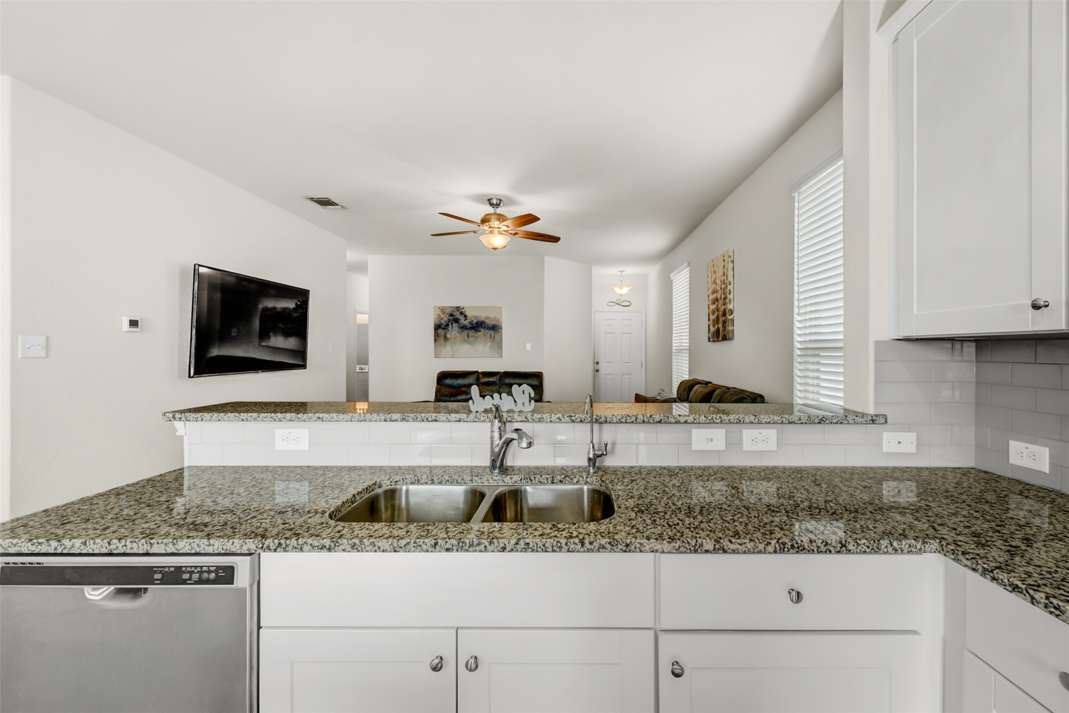 213 Ibis Falls Loop Jarrell, TX 76537 - Photo 12 of 37 A sleek kitchen features speckled granite countertops and a stainless steel sink, flowing into an open living area.