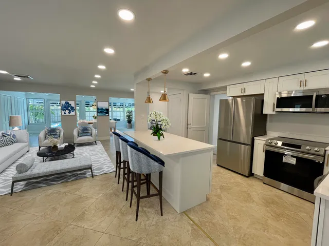 a kitchen with stainless steel appliances kitchen island granite countertop a refrigerator a stove a sink a dining table and chairs with wooden floor