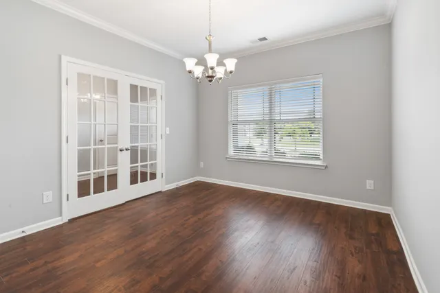 a view of a room with wooden floor chandelier and window