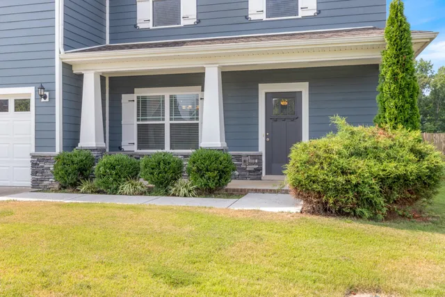 a front view of a house with a large window and potted plants