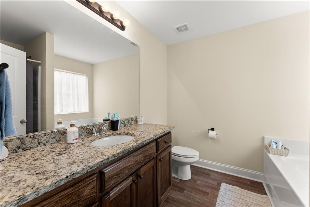 5430 Stepstone Way Gainesville, GA 30506 - Photo 19 of 39 a bathroom with a granite countertop sink a toilet and a large mirror