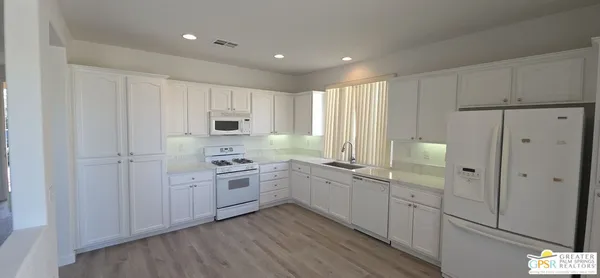 a kitchen with white cabinets and white appliances