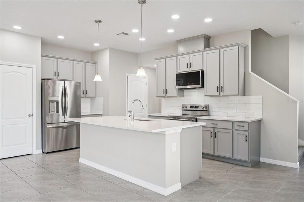 1915 Terrapin Road Ocoee, FL 34761 - Photo 3 of 25 a kitchen with stainless steel appliances granite countertop a stove top oven a refrigerator and white cabinets