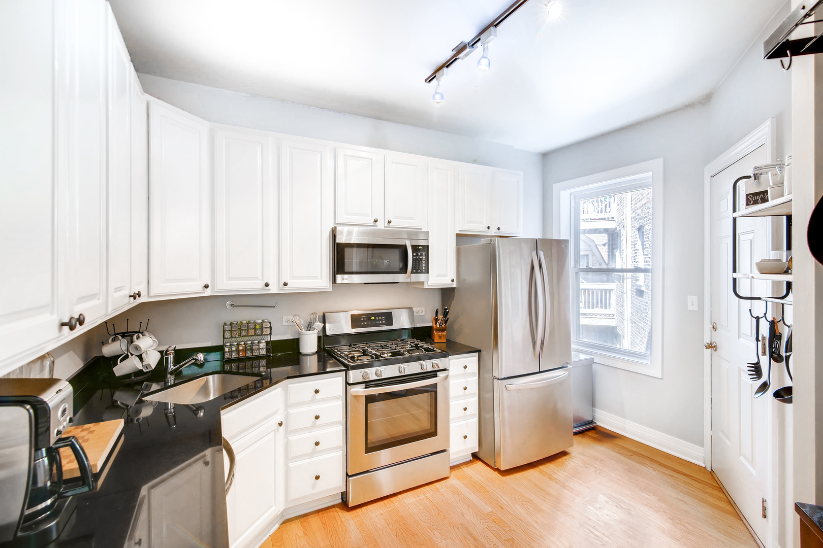 5707 North Ridge Avenue, Unit 2 Chicago, IL 60660 - Photo 6 of 11 a kitchen with granite countertop a refrigerator stove and white cabinets