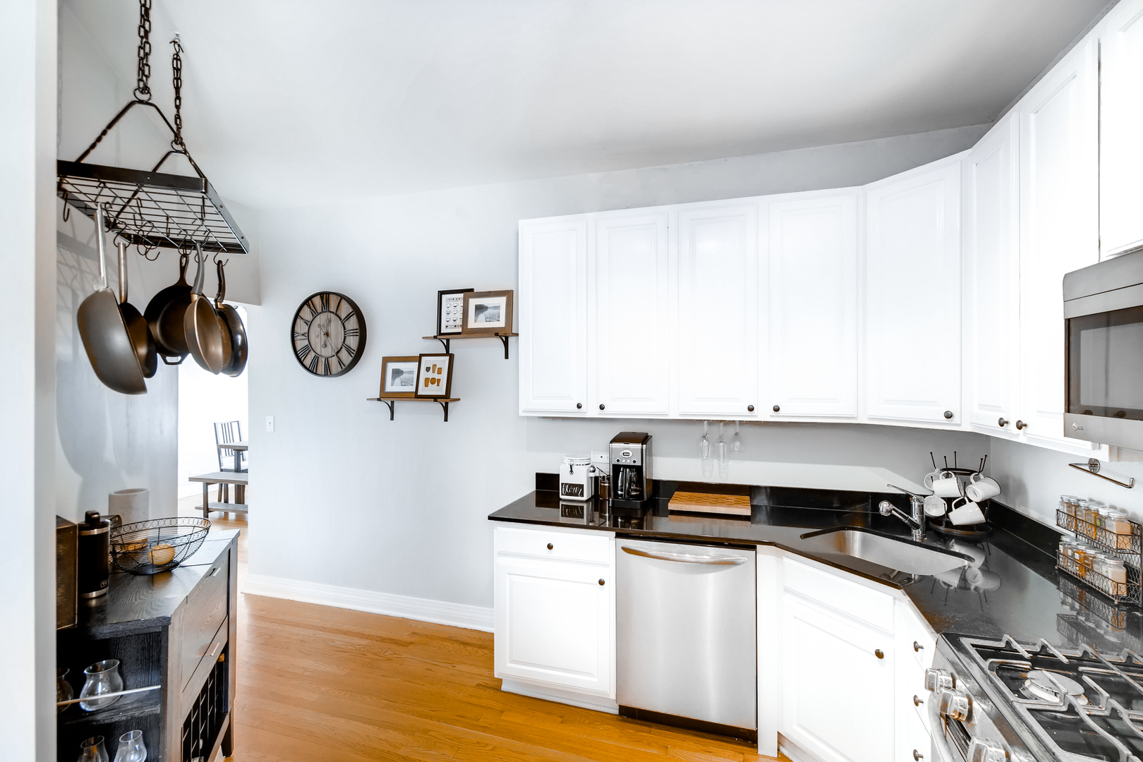5707 North Ridge Avenue, Unit 2 Chicago, IL 60660 - Photo 7 of 11 a kitchen with stainless steel appliances granite countertop a sink dishwasher stove and white cabinets with wooden floor