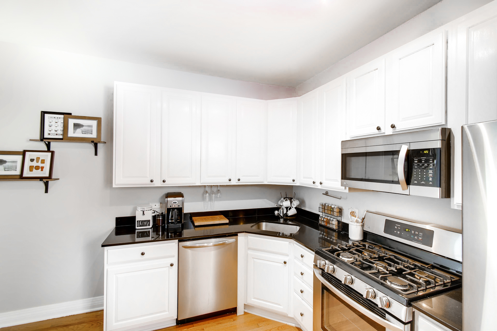 5707 North Ridge Avenue, Unit 2 Chicago, IL 60660 - Photo 8 of 11 a kitchen with stainless steel appliances a stove a microwave and white cabinets