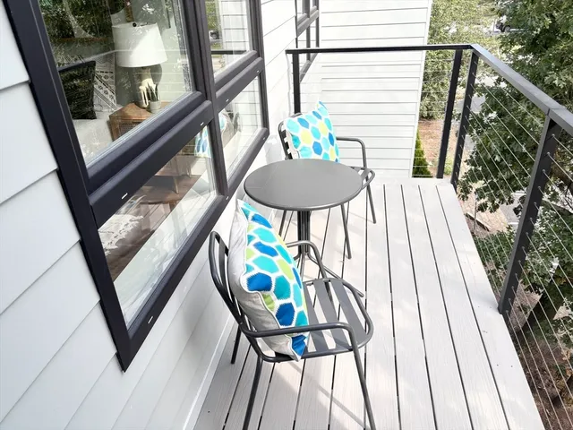 a balcony with wooden floor stairs and outdoor seating
