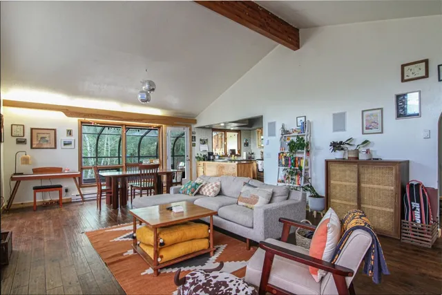 a living room with furniture and a dining table next to a large window