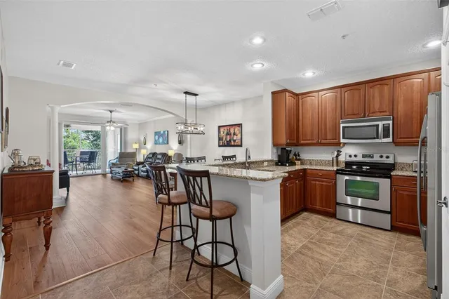a kitchen with stainless steel appliances granite countertop a refrigerator a stove microwave oven a sink dishwasher and white cabinets with wooden floor