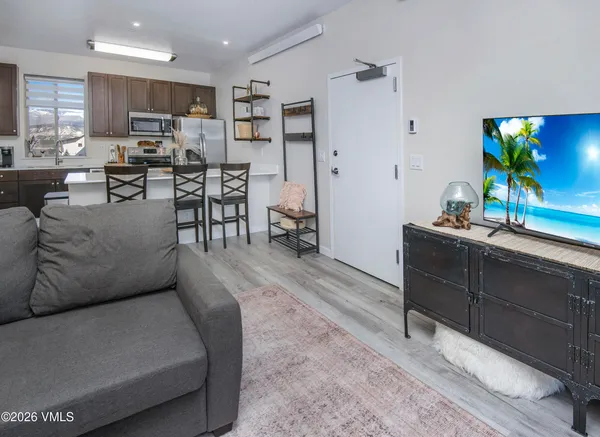 a living room with furniture kitchen view and a wooden floor