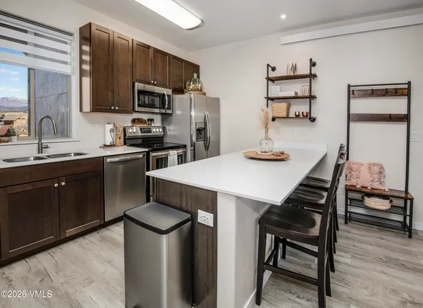 a kitchen with stainless steel appliances kitchen island granite countertop a sink a stove a refrigerator cabinets and chairs