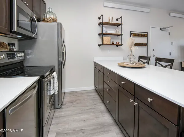 a kitchen with stainless steel appliances granite countertop a refrigerator a sink dishwasher and wooden cabinets with wooden floor