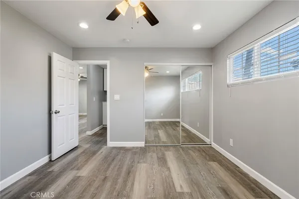 a view of empty room with wooden floor and fan