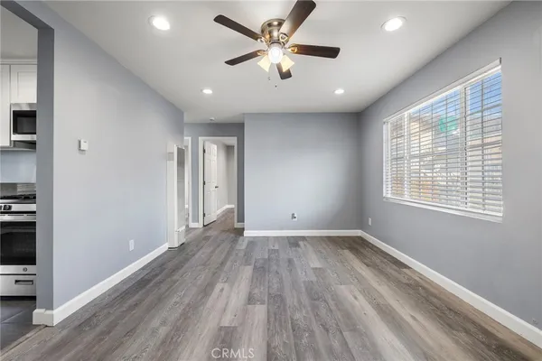 a view of an empty room with a window and wooden floor