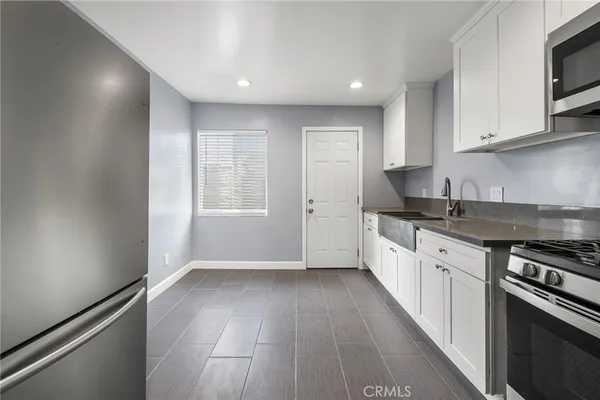 a kitchen with granite countertop a stove top oven a sink dishwasher and a refrigerator with wooden floor
