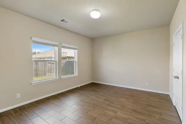 a view of an empty room with wooden floor and a window