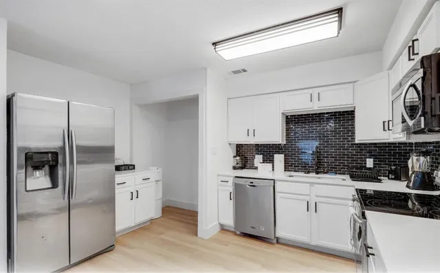 a kitchen with white cabinets and stainless steel appliances