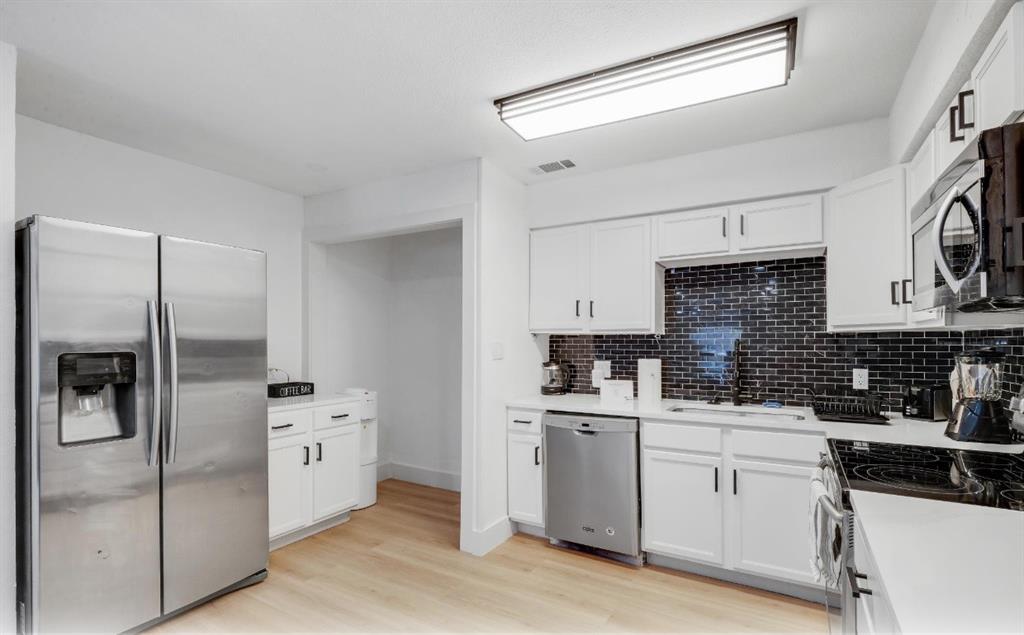 5041 Thunder Road Dallas, TX 75244 - Photo 5 of 20 a kitchen with white cabinets and stainless steel appliances