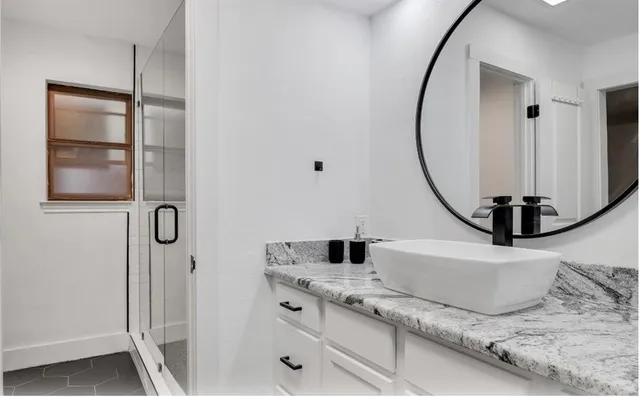 a bathroom with a granite countertop shower a mirror and a sink