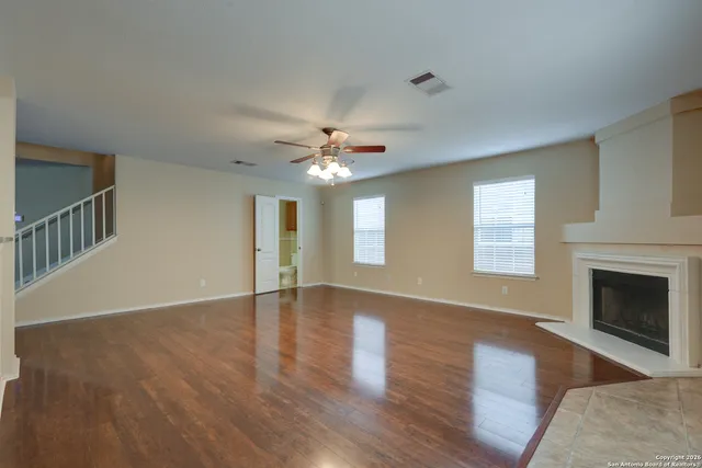 a view of an empty room with wooden floor fireplace and a window