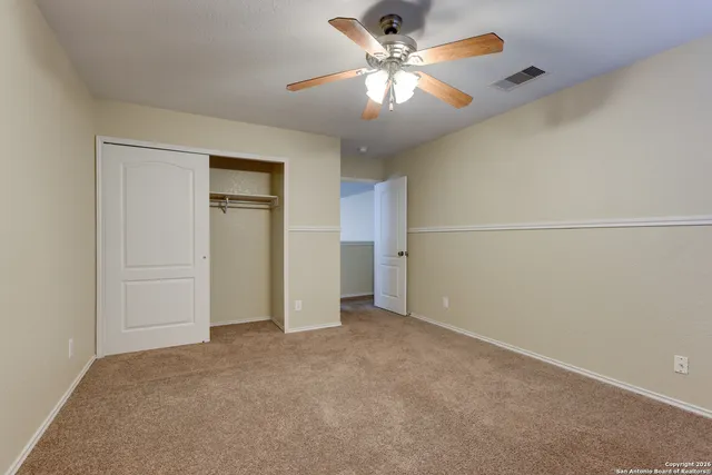 an empty room with closet and a ceiling fan