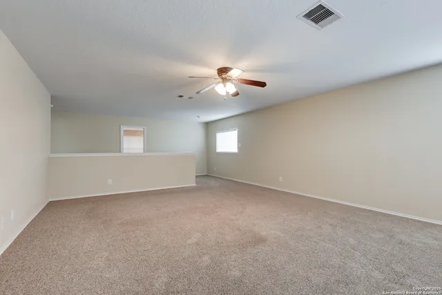a view of an empty room with a ceiling fan and window