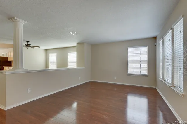 a view of an empty room with wooden floor and a window