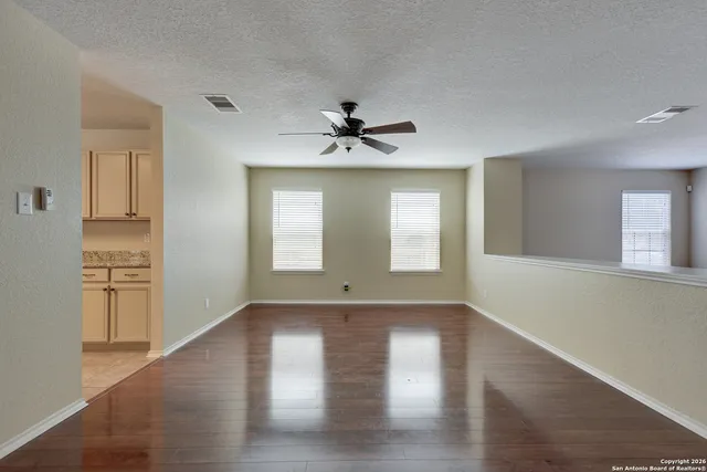 a view of an empty room with a window and wooden floor