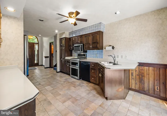 a large kitchen with stainless steel appliances granite countertop a refrigerator and a stove top oven