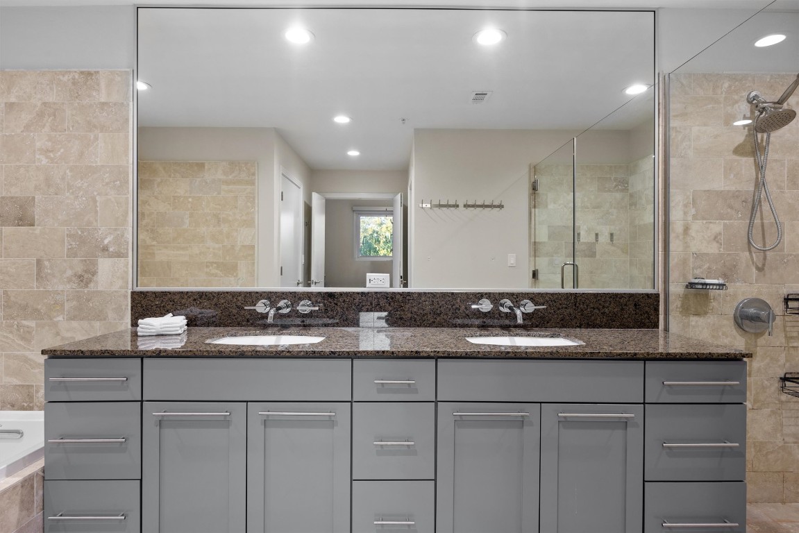 1600 Barton Springs Road, Unit 4205 Austin, TX 78704 - Photo 18 of 37 a bathroom with a granite countertop sink a mirror and a shower