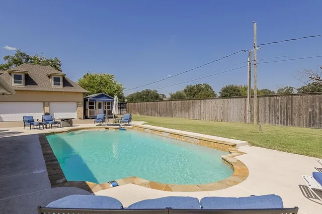 a view of a swimming pool with a patio and a yard