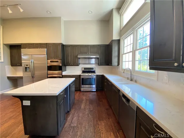 a kitchen with stainless steel appliances kitchen island granite countertop a sink stove refrigerator and a window