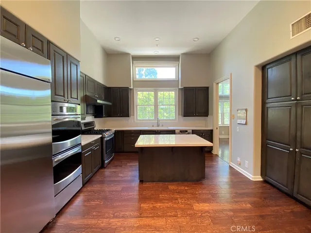 a large kitchen with stainless steel appliances wooden floor and a window
