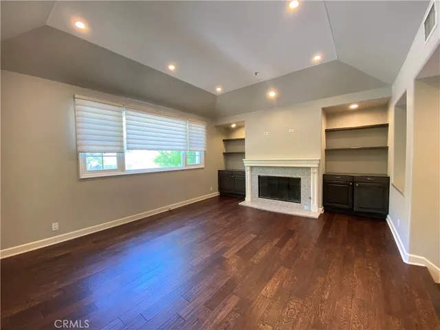 an empty room with wooden floor fireplace and windows