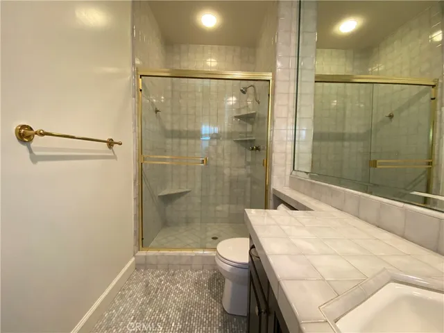 a bathroom with a granite countertop shower a sink and toilet